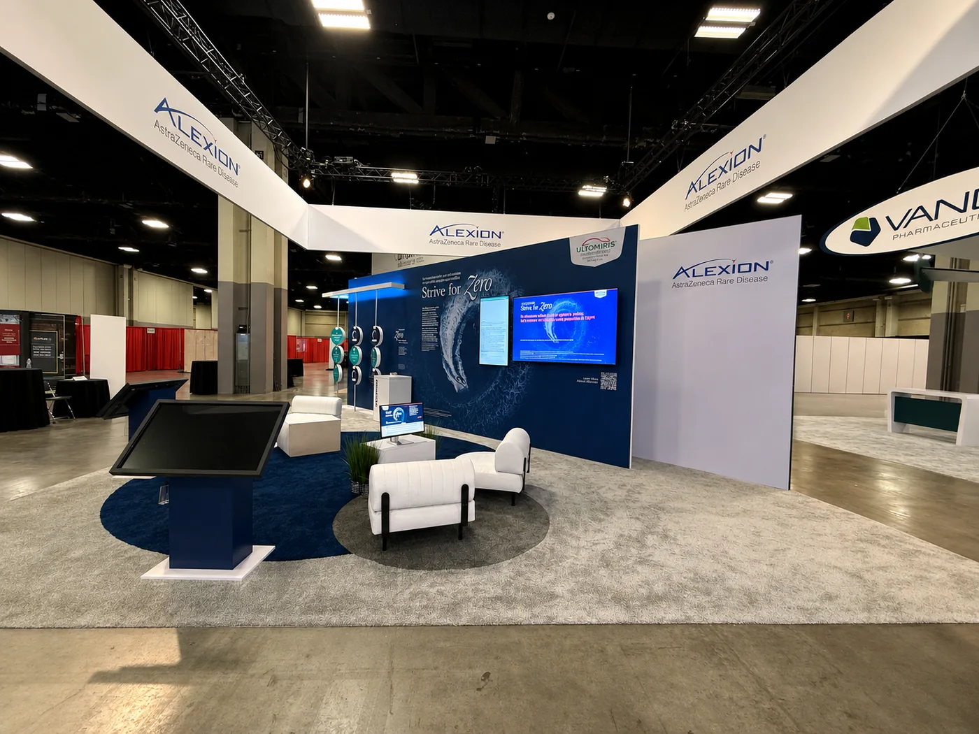 Completed Alexion trade show exhibit with custom walls, counters, monitor, and seating