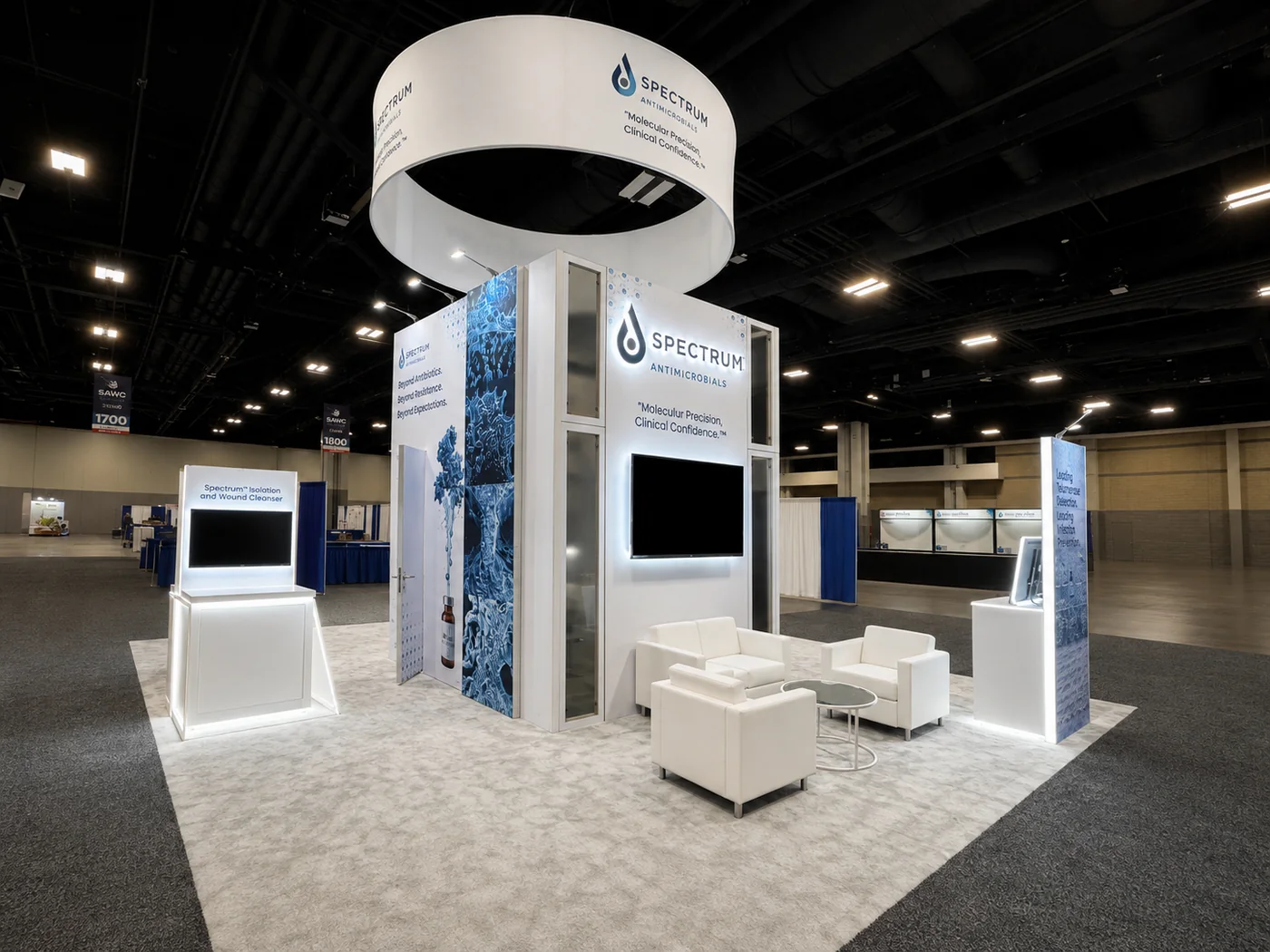 Completed Spectrum Antimicrobials trade show exhibit with hanging sign, illuminated displays, and seating